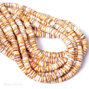 May include: Close-up of several strands of orange and white shell beads. The beads are flat, disc-shaped, and strung together. The beads have a natural, organic appearance, with variations in color and texture. The image is well-lit, and the beads are in sharp focus.