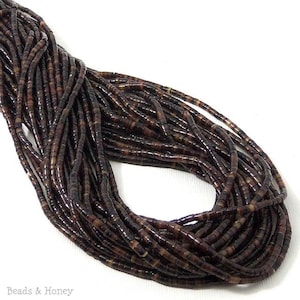 May include: A long strand of small, cylindrical beads in varying shades of dark brown, black, and tan. The beads are strung together in multiple parallel lines, creating a dense, textured appearance. The text Beads & Honey is visible.