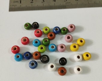 May include: Assortment of colorful ceramic beads in various shades of blue, green, red, yellow, brown, pink, black, and white. The beads are round with a hole in the center.