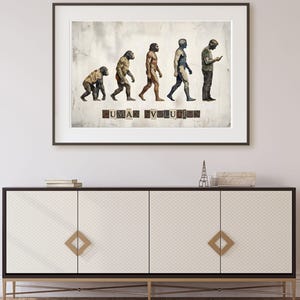 May include: Framed art print depicting human evolution, transitioning from ape-like figures to a person engrossed in a smartphone. The text "HUMAN EVOLUTION" is displayed at the bottom. The artwork is displayed above a white and black cabinet with gold hardware.