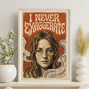 以下が含まれることがあります： メガネをかけた女性が描かれた額入りのアートプリント。大きな文字で「I NEVER EXAGGERATE」と書かれ、「I'VE TOLD YOU A BILLION TIMES」というフレーズがリボンに繰り返されています。背景は温かみのあるオレンジ色です。