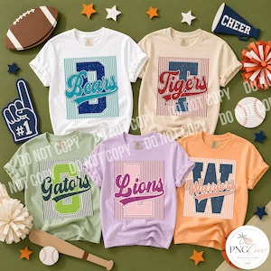 Pode incluir: Cinco t-shirts de manga curta e gola redonda em branco, bege, verde claro, lavanda e laranja. Cada t-shirt apresenta um gráfico central com um quadrado de riscas verticais, uma letra maiúscula grande e o nome de uma equipa em cursivo.
