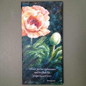 May include: A painting of a peach-colored poppy flower with green leaves and a bud. The painting has a dark blue background and a quote from Proverbs 11:21: "Whoever pursues righteousness and love finds life, prosperity and honor."