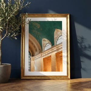 May include: A framed print featuring a detailed architectural interior. The image showcases a high ceiling with arched windows and ornate detailing. The color palette includes gold, green, and beige tones, creating a classic and elegant aesthetic. The print is displayed in a gold frame.