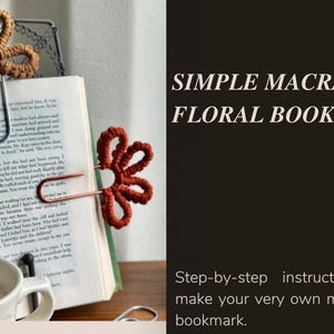 Puede incluir: Un marcapáginas floral de macramé en un libro. El marcapáginas está hecho de hilo marrón y rojo, con forma de flores, y sujeto a un clip de metal. El texto de la derecha dice "SIMPLE MACRAME FLORAL BOOKMARK".