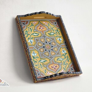 May include: Hand-painted wooden serving tray with a yellow background and intricate geometric and floral patterns in gray, blue, red, and green. The tray has a scalloped edge and a cutout handle. The brand name "tislitercrafts" is visible in the bottom left corner.