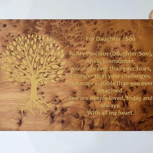 Pode incluir: Placa de madeira com um desenho de árvore e o texto "Para Filha / Filho". A placa tem um padrão de grão de madeira natural e uma ilustração de árvore dourada. O texto inclui uma mensagem inspiradora.