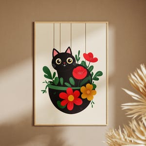 May include: A framed art print featuring a black cat in a hanging planter filled with red and yellow flowers and green leaves. The cat has yellow eyes and is smiling. The artwork is set against a beige background.
