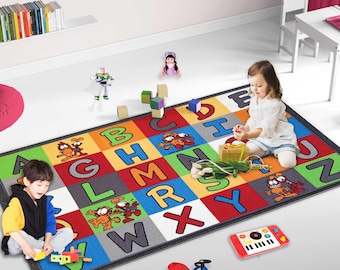 Puede incluir: Una alfombra rectangular para niños con un diseño de alfabeto colorido. La alfombra presenta letras grandes en bloques de varios colores, personajes de dibujos animados y un borde negro. Los juguetes para niños están esparcidos alrededor de la alfombra.