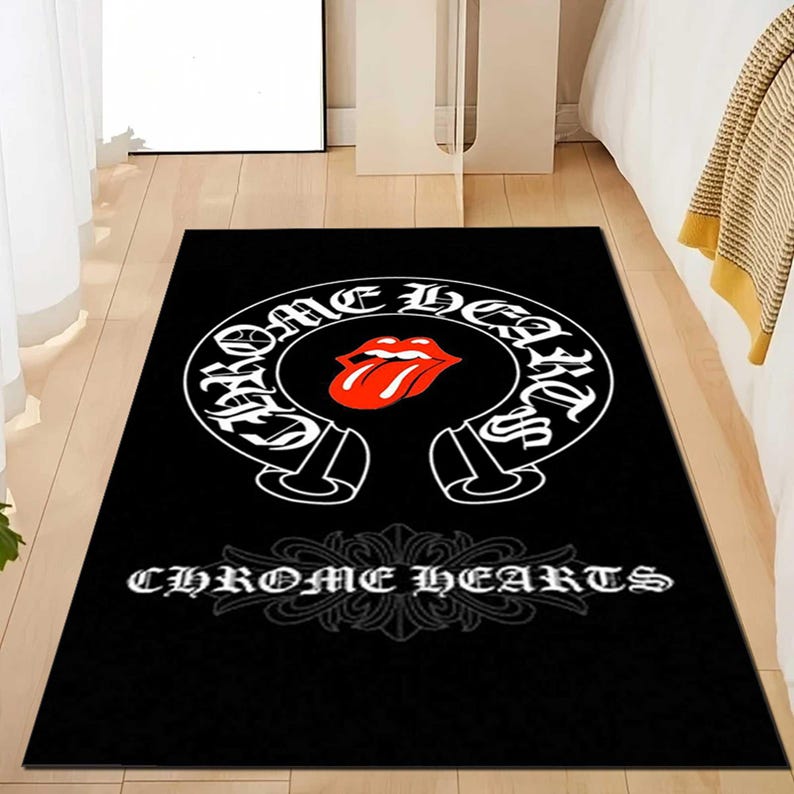 May include: Black rectangular area rug featuring the Chrome Hearts logo. The logo is a white horseshoe shape with the words "CHROME HEARTS" in a stylized font. Inside the horseshoe is a red tongue logo. The words "CHROME HEARTS" are also printed in white at the bottom.