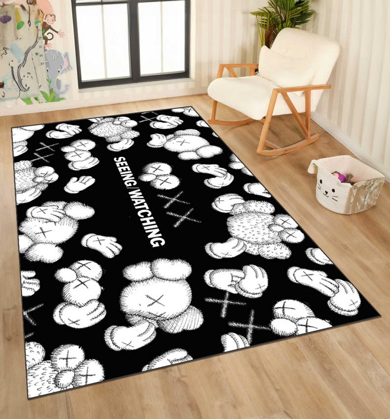 May include: Black rectangular rug featuring a repeating pattern of white cartoon figures with X-shaped eyes and crossbones. The words "SEEING WATCHING" are printed vertically in white.