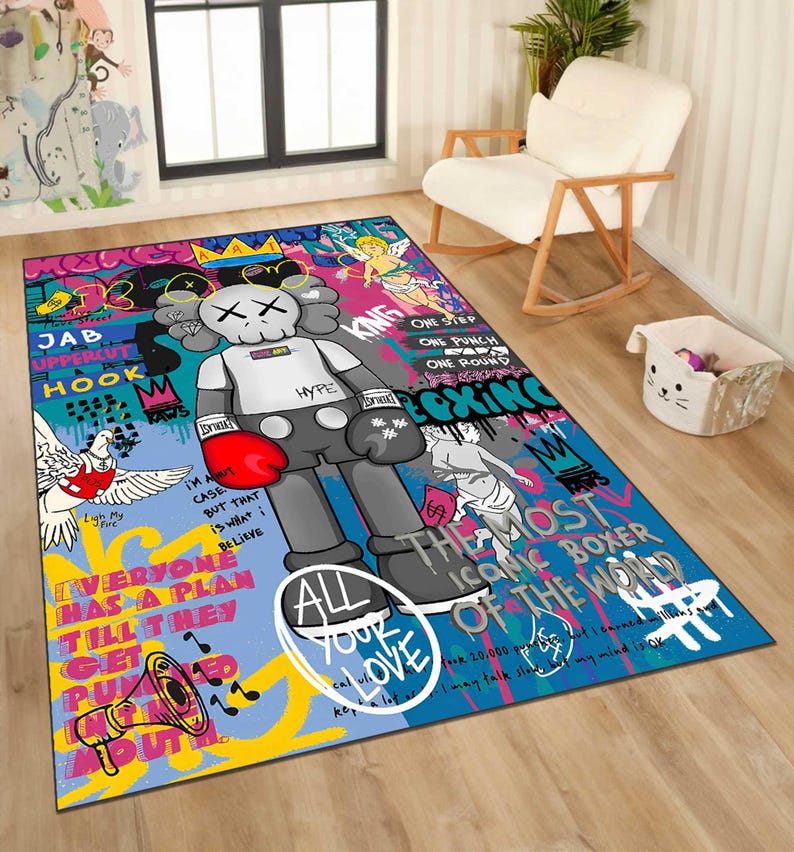 May include: A rectangular area rug with a colorful graffiti design. The rug features a large cartoon figure with boxing gloves, surrounded by text and illustrations. The color palette includes blue, red, black, and white.