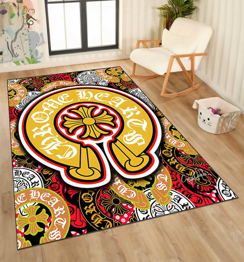 May include: A rectangular area rug with a bold design. The rug features a large, yellow horseshoe shape with the words "Chrome Hearts" in white. The background is a mix of red, black, and white patterns with floral and cross motifs.