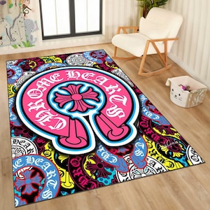 May include: A rectangular area rug with a vibrant, multi-colored design. The rug features a large, pink and white emblem with the words "Chrome Hearts" and a cross-shaped design. The background is filled with various patterns and colors, including blue, yellow, and black.