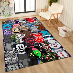 May include: A rectangular area rug featuring a repeating pattern of stylized bear figures in various colors and designs. The rug includes text that reads "HIGH" and "BEARBRICK". The rug is placed on a wooden floor.