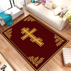 Puede incluir: Una alfombra rectangular con fondo burdeos y diseño de cruz ortodoxa dorada. La alfombra tiene un borde dorado y detalles de hojas doradas en cada esquina. La alfombra está colocada sobre un suelo de madera.