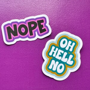 May include: Two stickers on a purple background. One sticker says "NOPE" in black letters with a pink and purple border. The other sticker says "OH HELL NO" in white letters with a teal and gold border.