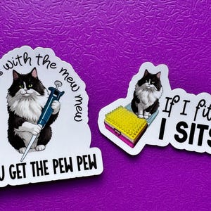 May include: Two stickers with cat illustrations on a purple background. One sticker features a black and white cat holding a pipette with the text "If you mess with the mew mew, you get the pew pew." The other says "If I fits, I sits."