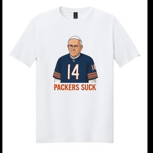 May include: White t-shirt featuring a cartoon image of a man wearing a football jersey with the number 14. The jersey is navy blue with orange stripes. The text "PACKERS SUCK" is printed below the image.