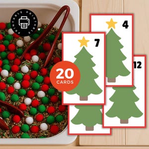 May include: A sensory bin with red, green, and white pom-poms and cards featuring green Christmas trees with numbers 4, 7, and 12. A red circle reads "20 cards". A pair of red tongs is in the bin.