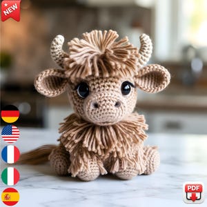 May include: A crocheted Highland cow plush toy in shades of tan and brown. The handmade cow has large, expressive black eyes, small horns, and a fluffy mane and fringe. The plush is sitting on a white surface.