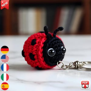 May include: A handmade crochet ladybug keychain. The ladybug is red and black with large googly eyes and a silver keychain ring. The word "NEW" is in a red banner in the top left corner.