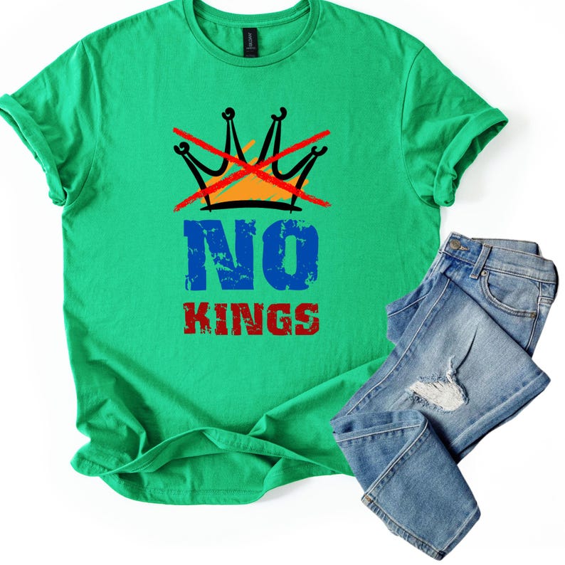 May include: A green t-shirt with the words "NO KINGS" in blue and red, and a crossed-out crown graphic. The shirt is paired with a pair of blue jeans.
