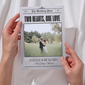 May include: A wedding announcement designed as a newspaper front page. The headline reads "TWO HEARTS, ONE LOVE" above a photo of a couple embracing in a field. The names "ESTELLE & BENJAMIN" are printed below the photo.