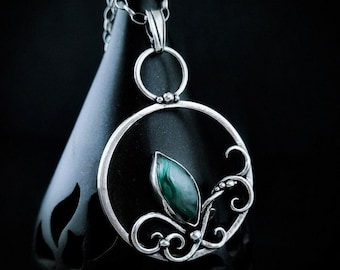 Malachite enchanted in sterling silver, asymmetrically shackled, wrapped in filigree twigs.