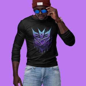 May include: Black long-sleeve shirt featuring a stylized purple and blue graphic design. The design has a dripping effect. The person in the image is wearing a maroon beanie and blue sunglasses.