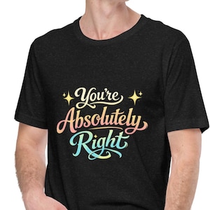Puede incluir: Camiseta gris oscuro con el texto "You're Absolutely Right" en una fuente cursiva colorida con acentos de estrellas. La camiseta es de cuello redondo.
