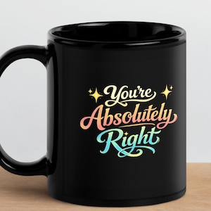 Puede incluir: Taza de cerámica negra con el texto "You're Absolutely Right" en escritura colorida. La taza tiene un asa curva y está sobre una superficie de madera.