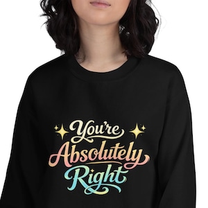 Puede incluir: Sudadera negra con el texto "You're Absolutely Right" en una fuente cursiva colorida. El texto está en tonos de rosa, amarillo y azul. La sudadera es de cuello redondo.
