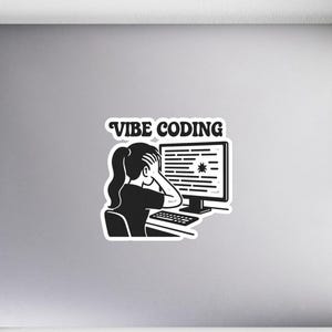May include: A black and white sticker featuring the text "Vibe Coding." The sticker depicts a person sitting at a computer, looking stressed. The computer screen displays lines of code. A notebook, pen, and mouse are also visible.