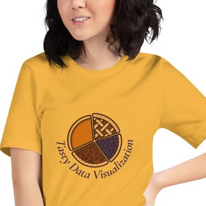Puede incluir: Camiseta amarilla mostaza con un diseño de gráfico circular y las palabras "Tasty Data Visualization" en círculo. El gráfico circular está dividido en cuatro secciones con diferentes patrones y colores. La camiseta es de material suave.