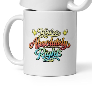 Puede incluir: Dos tazas de cerámica blanca apiladas. Cada taza tiene el texto "You're Absolutely Right" en una fuente retro colorida con estrellas. Las tazas tienen un asa estándar.