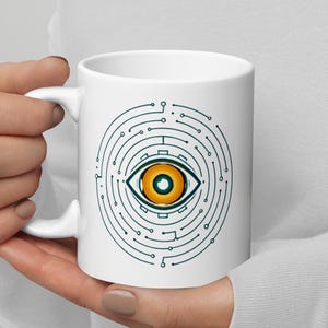 Op de afbeelding: Witte keramische mok met een gestileerd oogontwerp. Het oog is geel en oranje, omgeven door een printplaatachtig patroon in blauwgroen. De mok heeft een gebogen handvat en een glanzende afwerking.