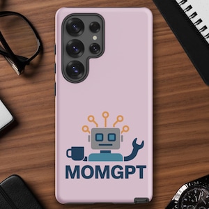 May include: A pale pink phone case with a robot design, a wrench, a coffee cup, and the text "MOMGPT" in blue. The case has multiple camera lenses. Office supplies surround the phone case.