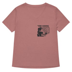 Puede incluir: Camiseta con cuello en V de color rosa polvoriento con un gráfico negro de una persona frente a una computadora y el texto "VIBE CODING". El gráfico muestra a una persona con la mano en la cabeza, mirando una pantalla de computadora.