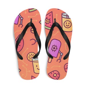 Puede incluir: Un par de chanclas naranjas con un patrón repetido de gráficos de dibujos animados coloridos, que incluyen un helado, una bebida sonriente y una rodaja de sandía. Las chanclas tienen correas negras.