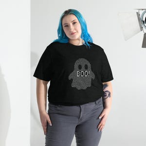 May include: Black t-shirt with a white ghost design made of binary code. The ghost has the word "BOO!" in the centre. The shirt is worn with grey trousers.