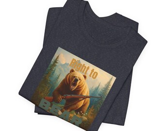 Puede incluir: Camiseta de cuello en V gris oscuro con un gráfico de un oso pardo sosteniendo un rifle, con el texto "Right to BEAR". El oso está situado contra un fondo de bosque y montaña.