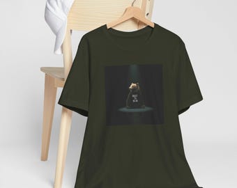 Puede incluir: Camiseta verde oscuro con un gráfico de un oso que lleva una camiseta con el texto "Respect the Grind". El oso está centrado en un fondo oscuro, iluminado por un foco. Una gorra de béisbol blanca descansa sobre una silla de madera.