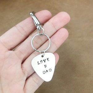 May include: Silver guitar pick keychain with the text "LOVE U DAD" engraved on it.