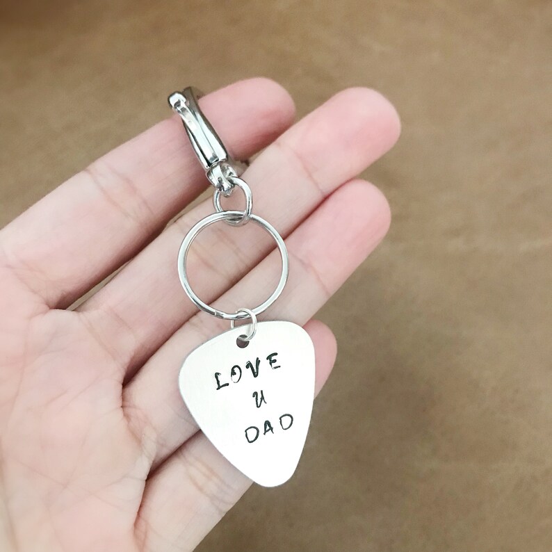 May include: Silver guitar pick keychain with the text "LOVE U DAD" engraved on it.