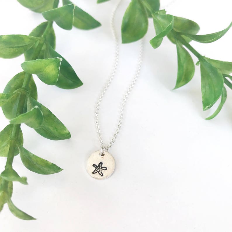 May include: A silver necklace with a small round pendant featuring a simple starfish design.