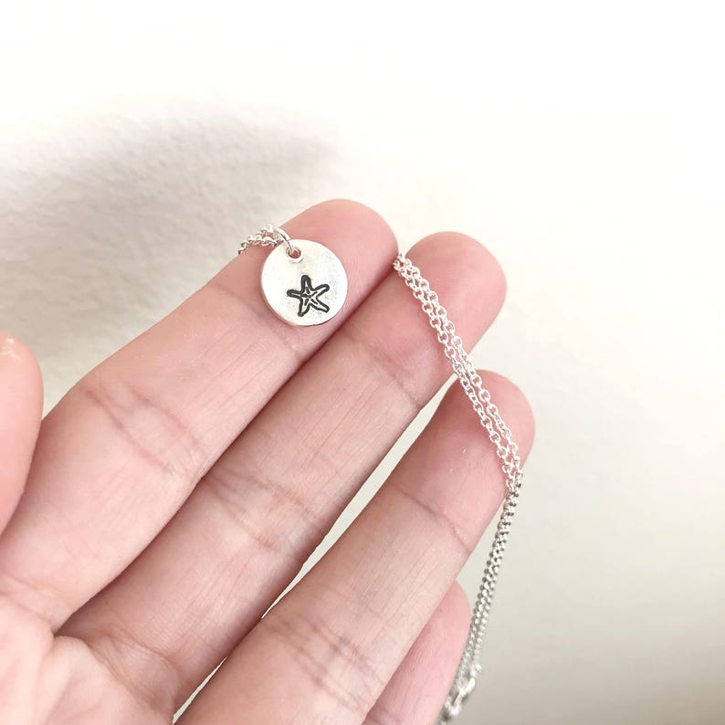 May include: A silver necklace with a small round pendant featuring a starfish design.