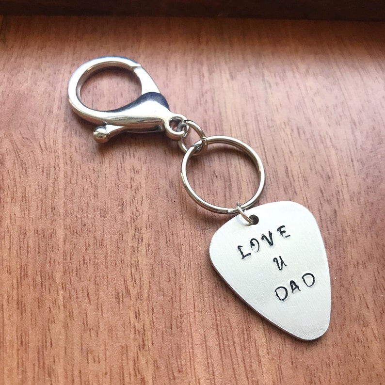 May include: Silver guitar pick keychain with the text "LOVE U DAD" engraved on it.