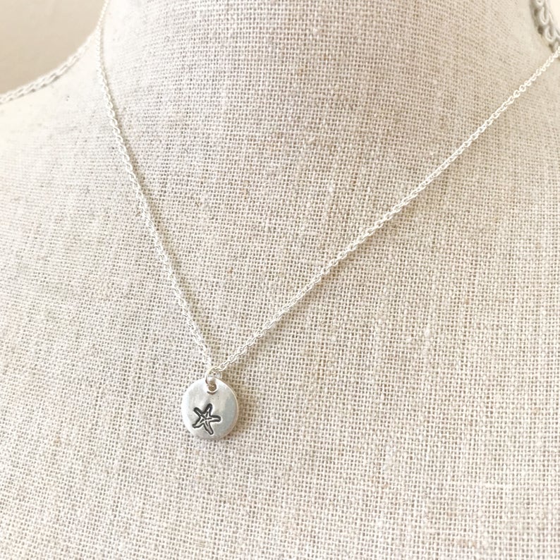May include: A silver chain necklace with a small silver pendant featuring a starfish design.