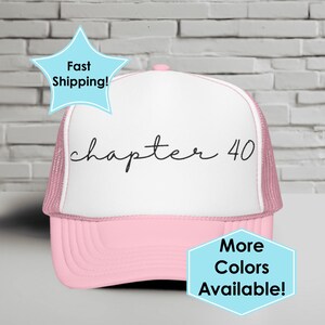 May include: A pink and white trucker hat with the text "chapter 40" in black script. The hat has a pink brim and mesh back. A light blue star-shaped graphic says "Fast Shipping!" and a light blue hexagon graphic says "More Colors Available!"